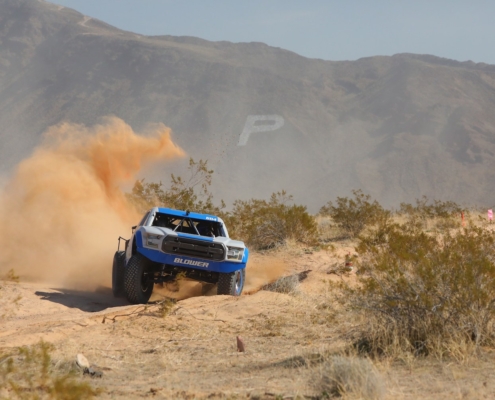 Blower Motorsports truck racing off-road with mountains in the background