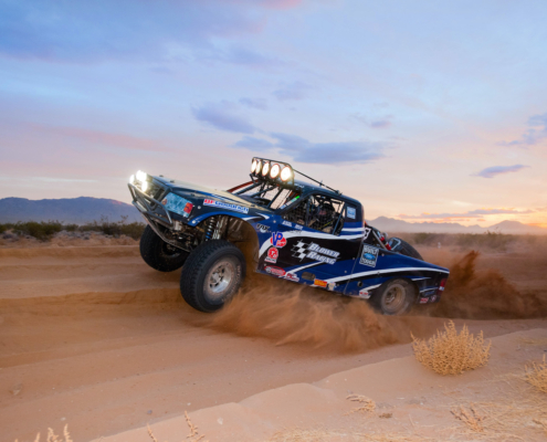 Blower Racing truck kicking up dirt in the desert at an off-road race